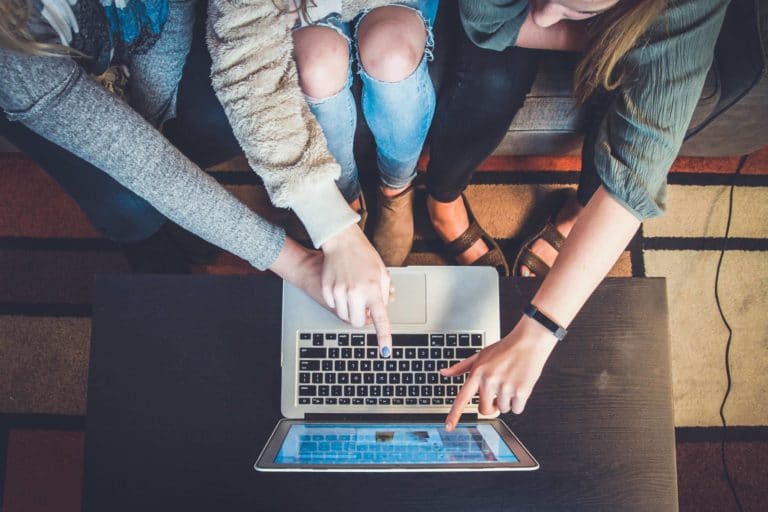 A group of people pointing at a computer screen