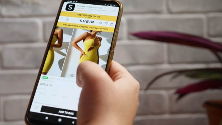 image of a person holding a phone with the shein affiliate program screen on the screen of the phone